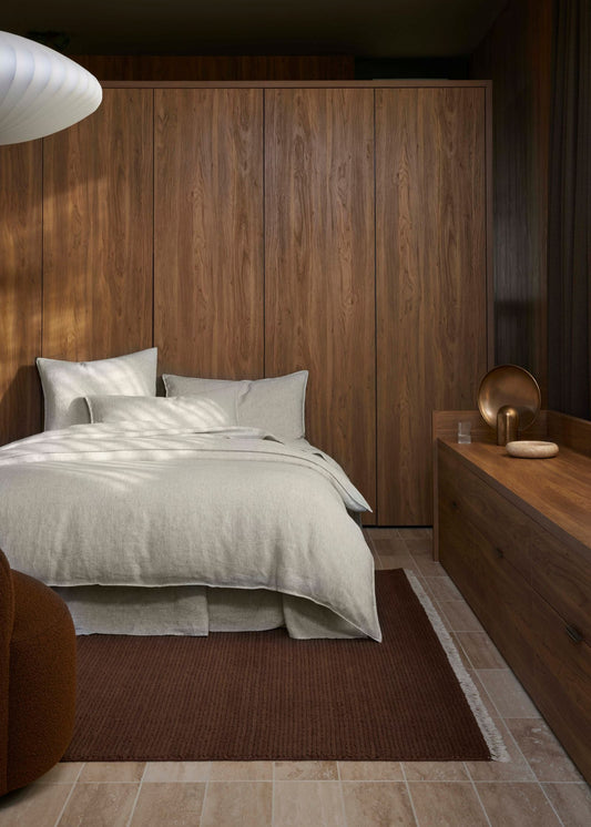 Modern bedroom with wooden walls and a bed with white bedding.