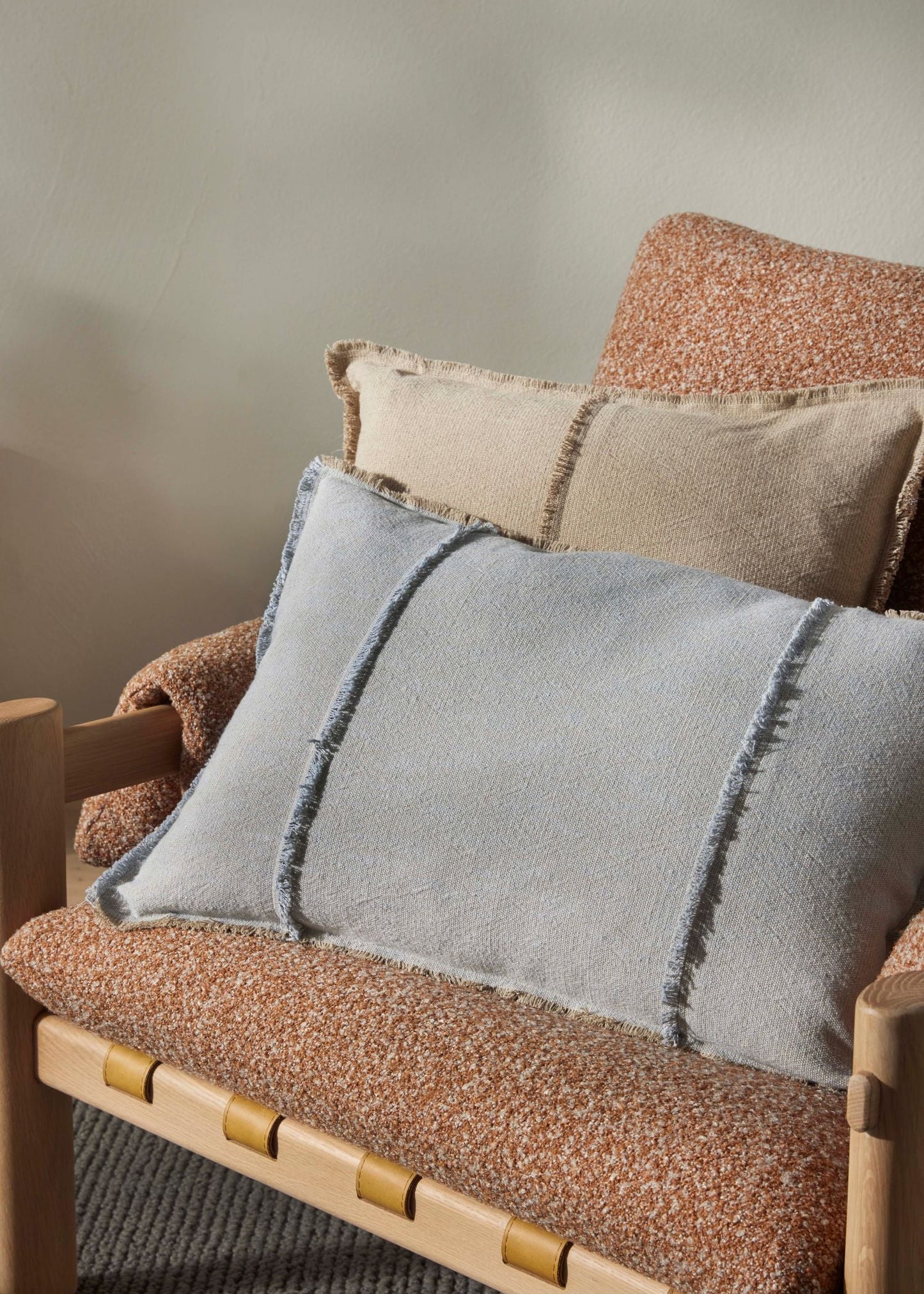 Decorative pillows on a textured chair with a neutral background