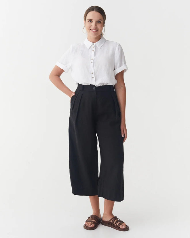 Person wearing a white shirt and black pants on a white background