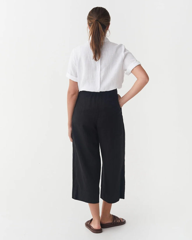 Person wearing a white shirt and black pants on a white background