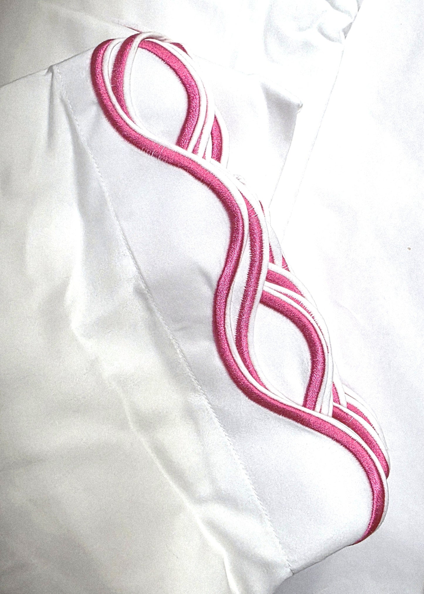 White fabric with pink embroidery on a white background