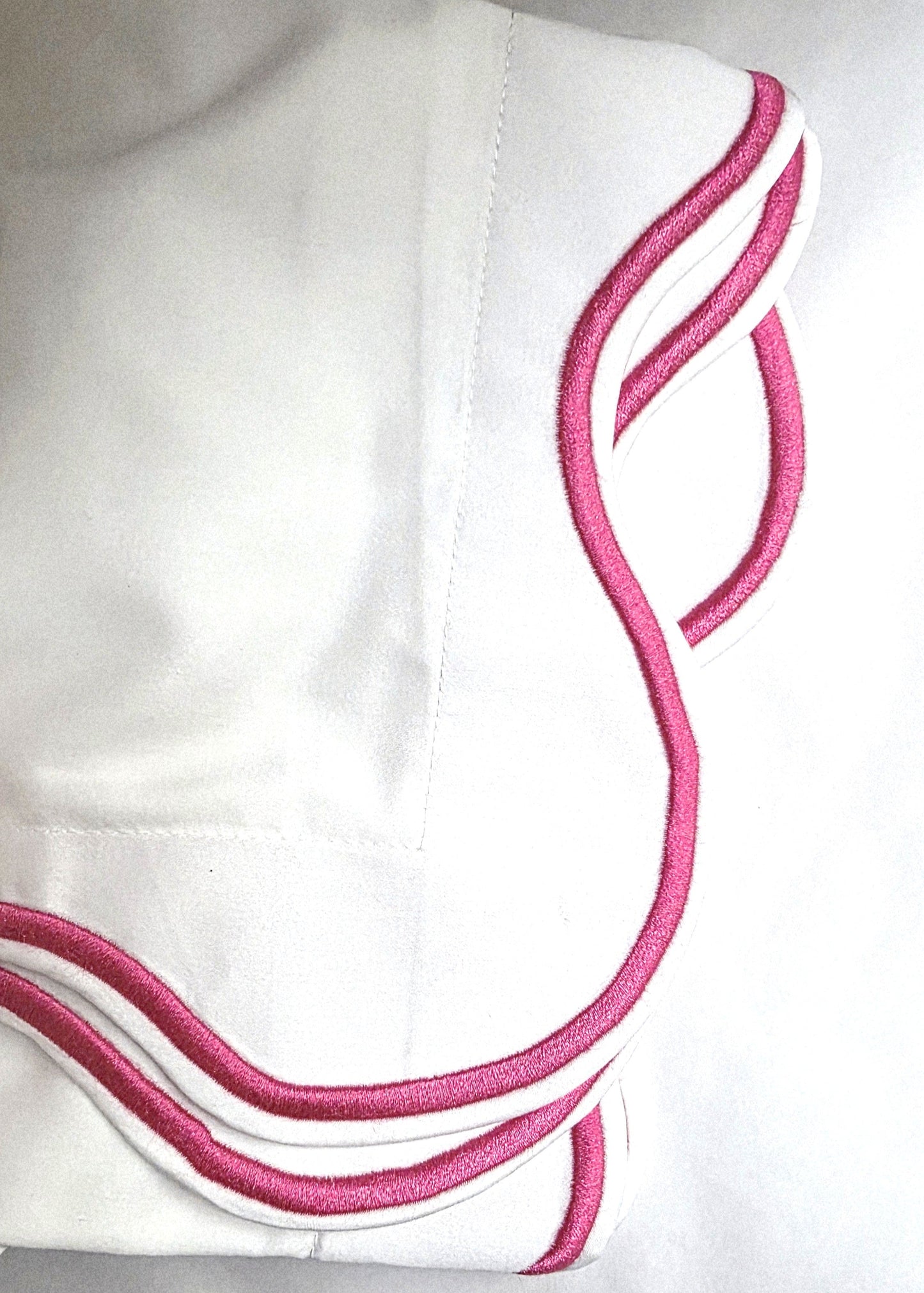 White fabric with pink embroidery on a white background