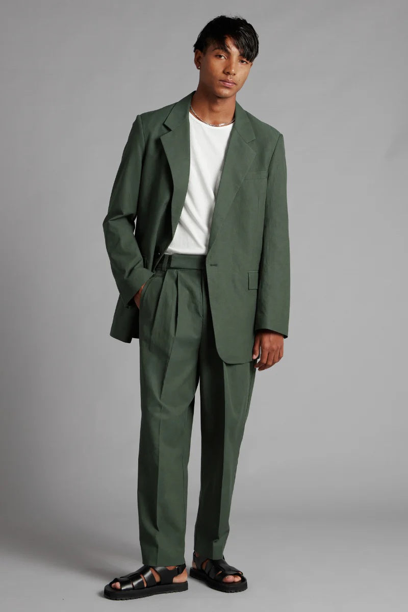 Man wearing a green suit with a white shirt on a gray background