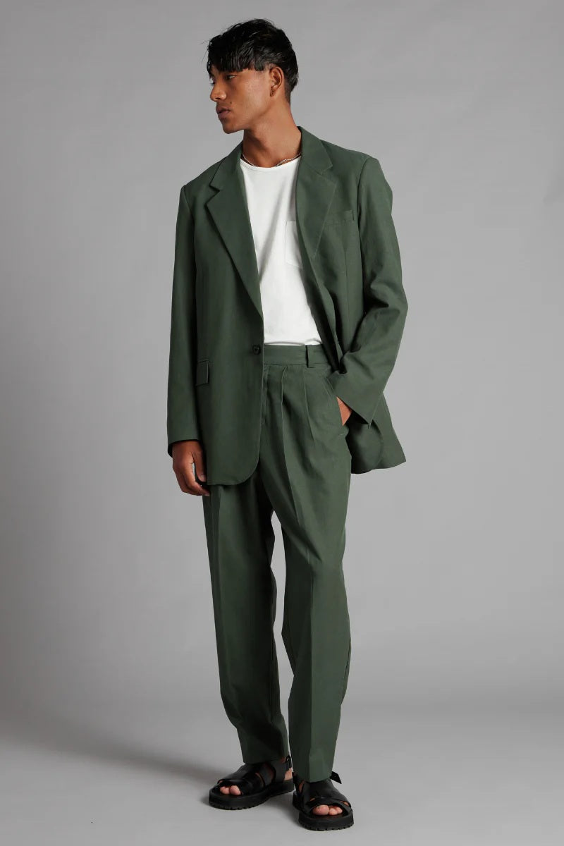 Man wearing a green suit with a white shirt on a gray background