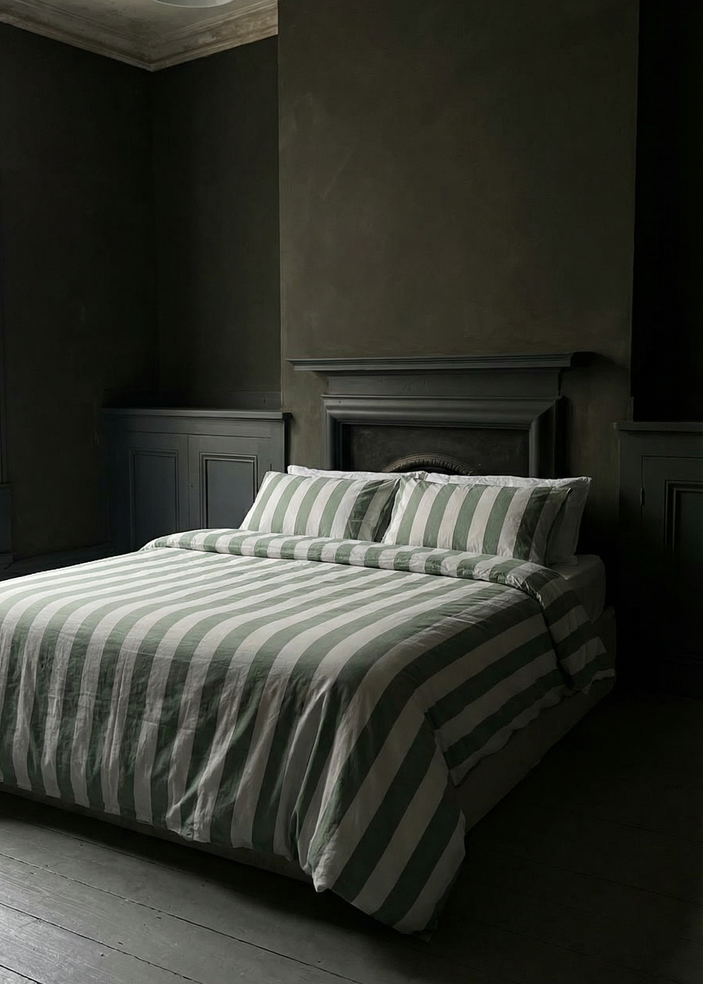 Dark bedroom with striped bedding and wooden floor