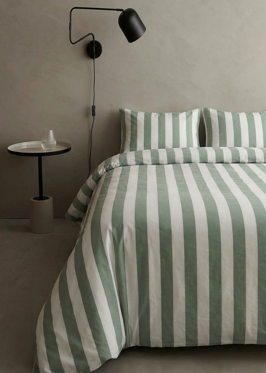 Bed with green and white striped bedding in a minimalistic room.