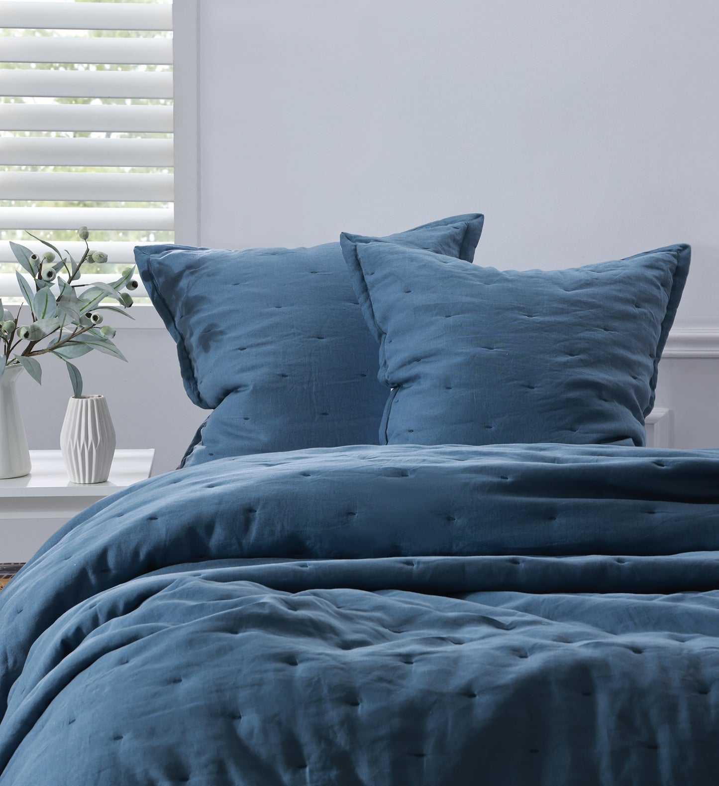 Blue textured duvet set on a bed with pillows in a bedroom setting.