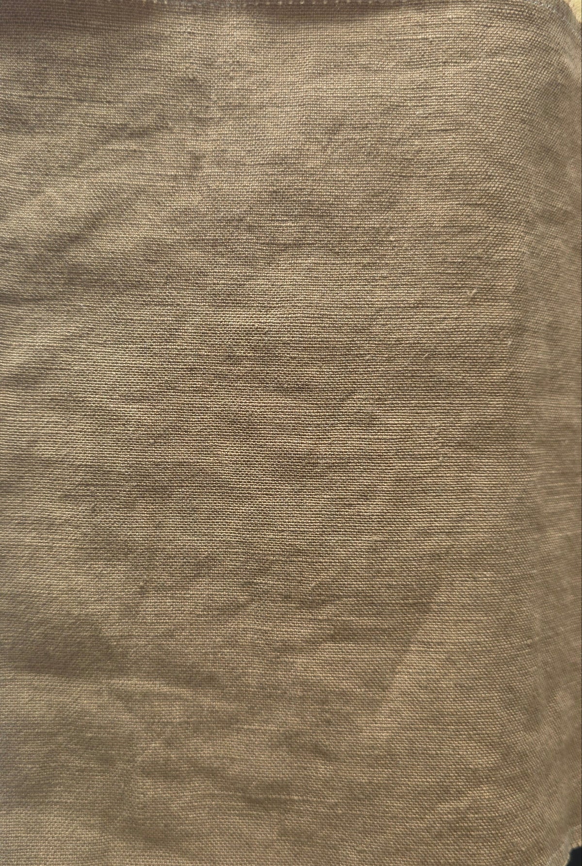 A square piece of tan woven fabric or felt material with a coarse, textured surface, laid flat on a white lined notebook page.