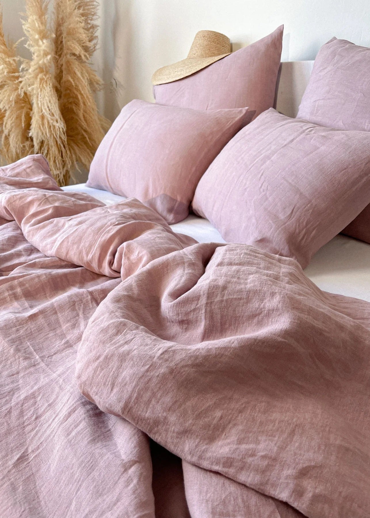 Pink bedding set with pillows on a bed in a softly lit room.