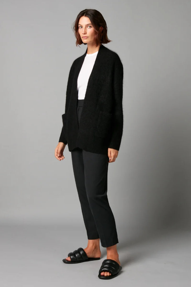 Person wearing a black blazer, white shirt, and black pants on a gray background