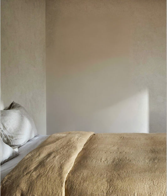 Bed with beige bedding against a neutral wall