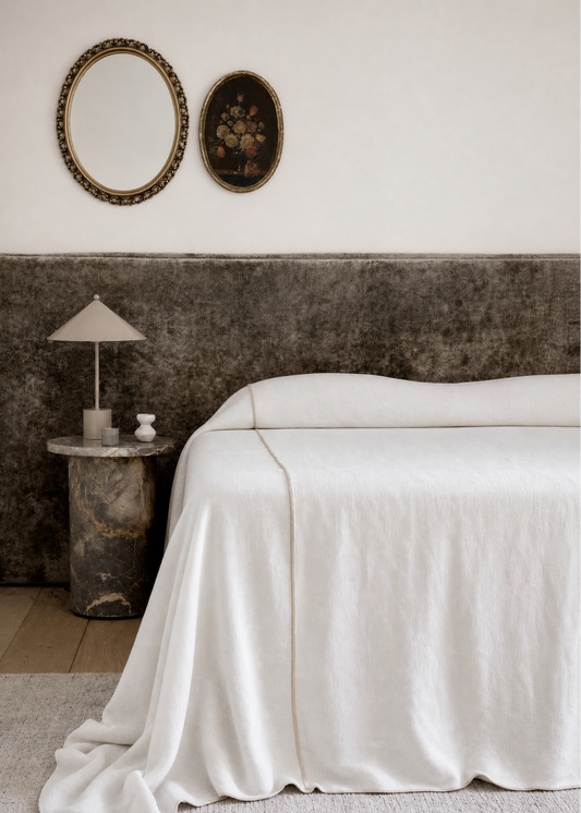 Bedroom with a large bed, side table, and decorative mirrors on the wall.