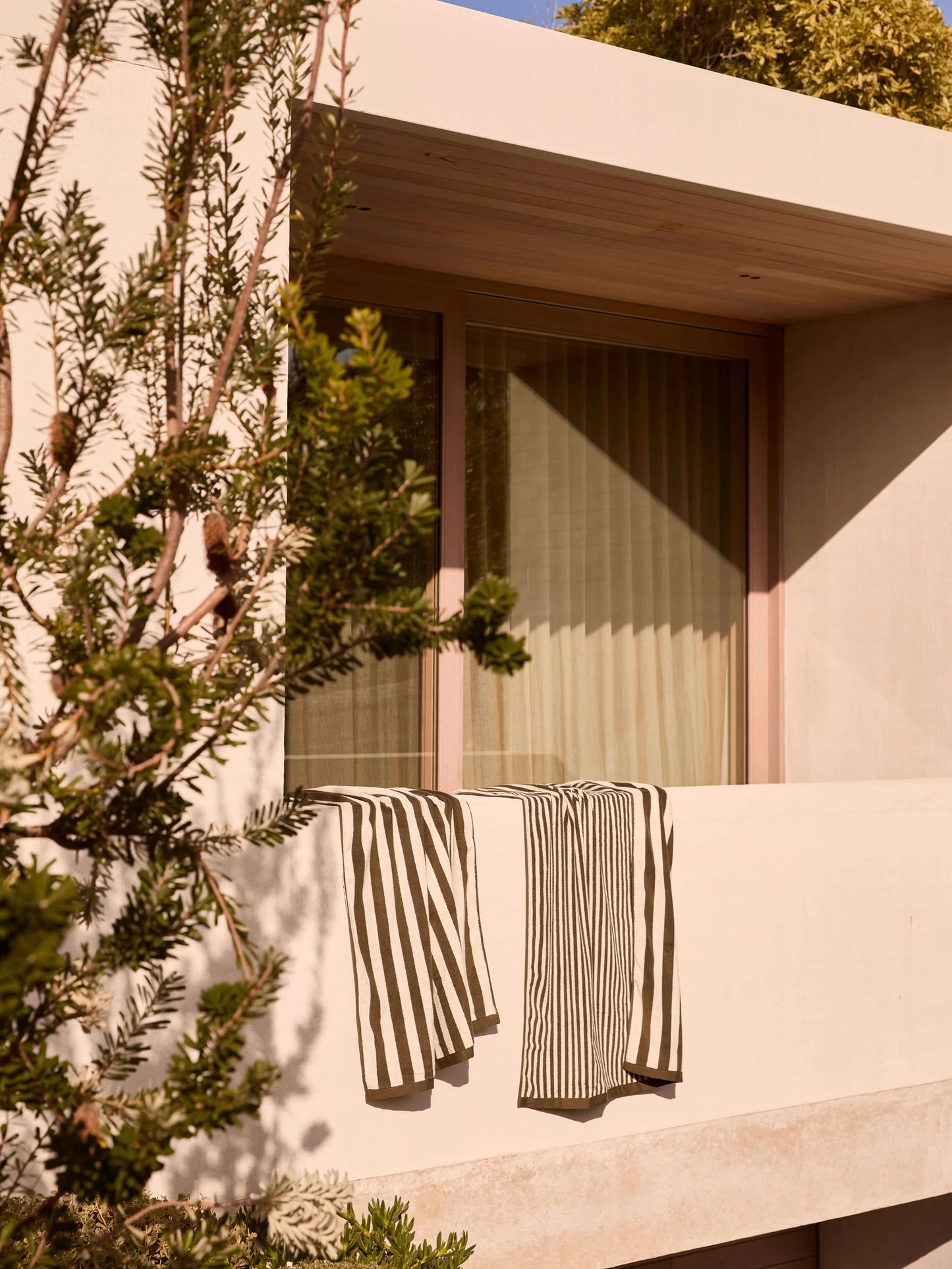 Striped towel hanging on a balcony with a modern building and trees in the background