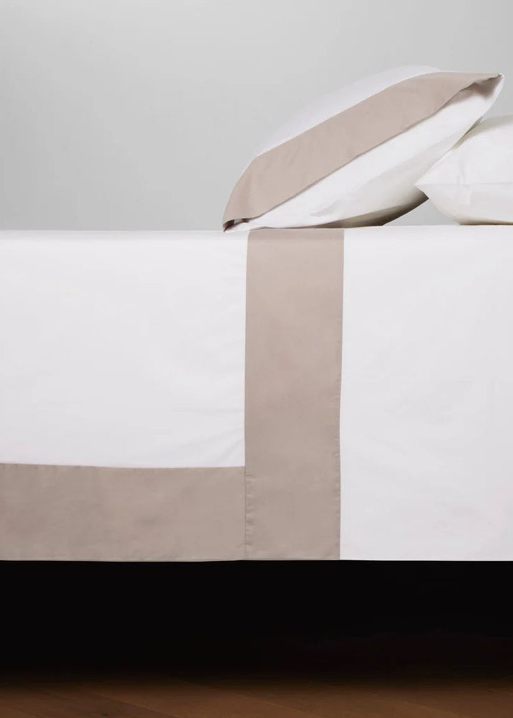A taupe and white duvet cover set on a bed, with a duvet cover and two pillowcases displayed in a contrasting color arrangement.