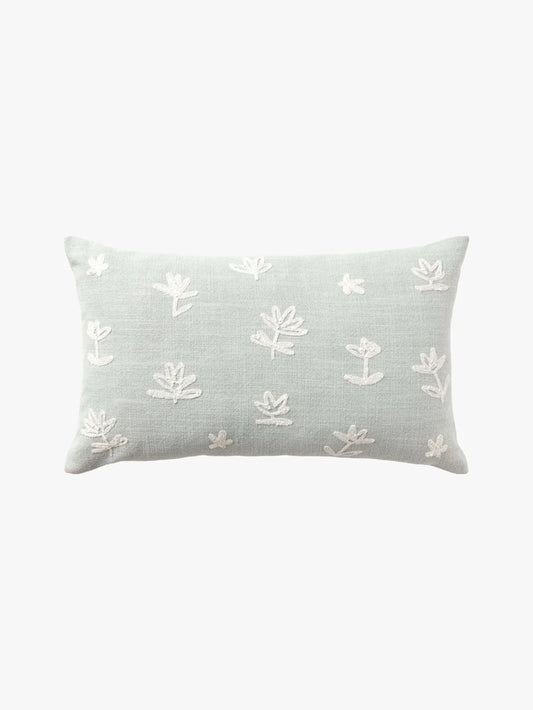 A rectangular light sage green throw pillow with white embroidered floral motifs, shown against a plain white background.