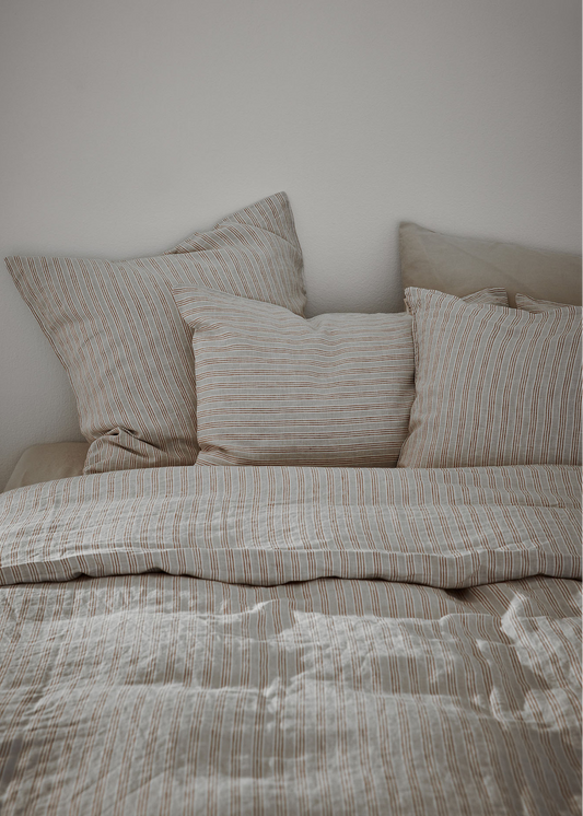 Textured bedspread and pillows on a bed against a plain wall