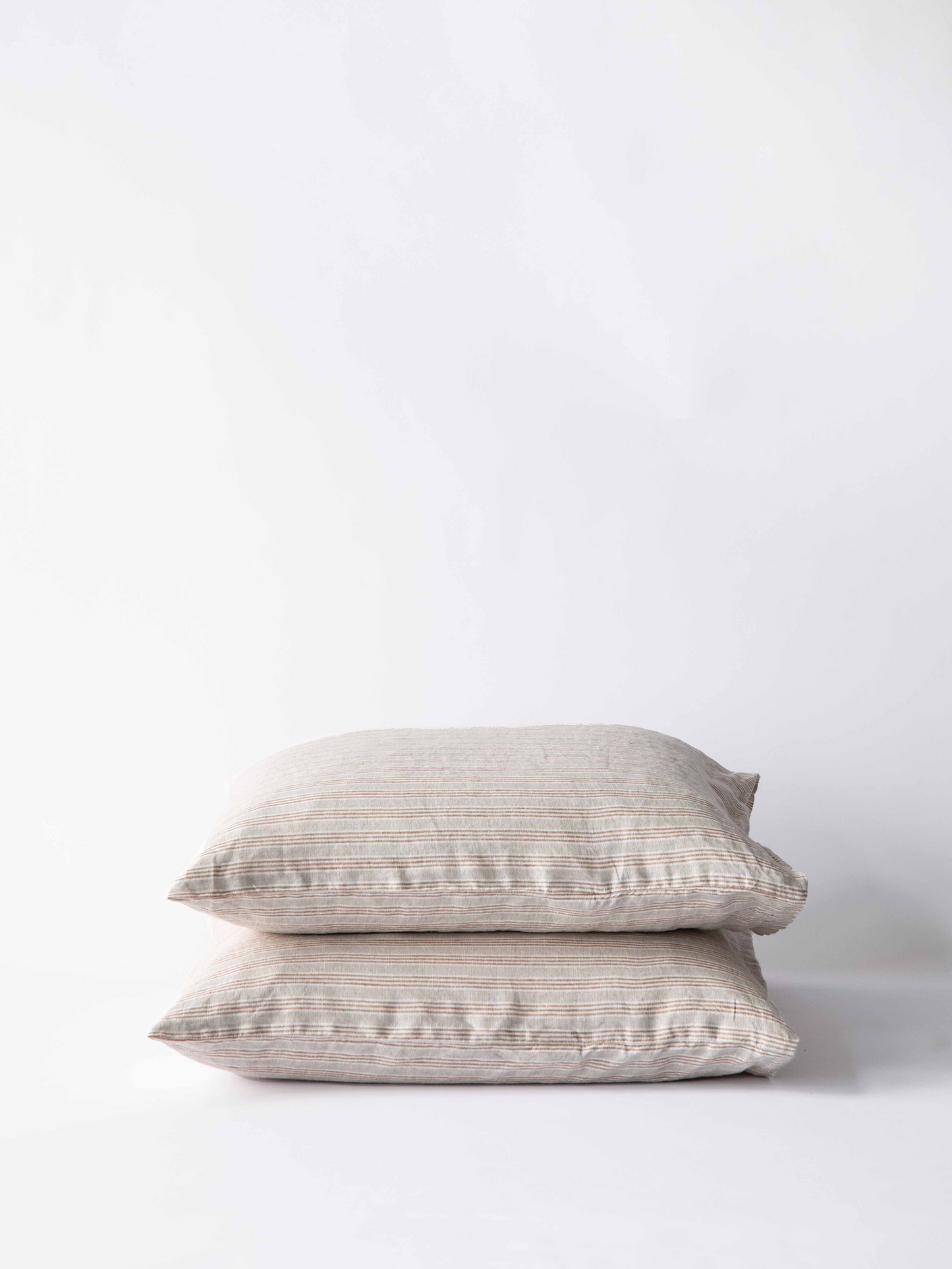 Two beige pillows stacked on a white background