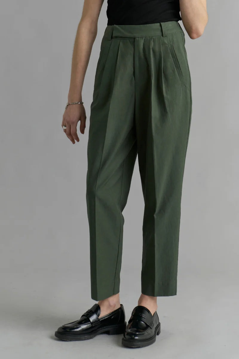 Person wearing green pleated pants on a plain background