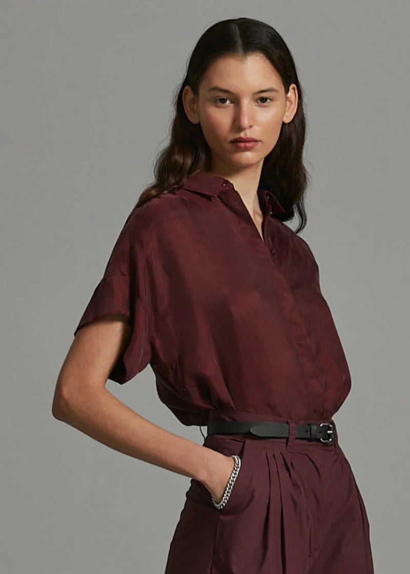 Woman wearing a burgundy outfit against a gray background