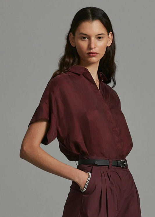 Woman wearing a burgundy outfit against a gray background