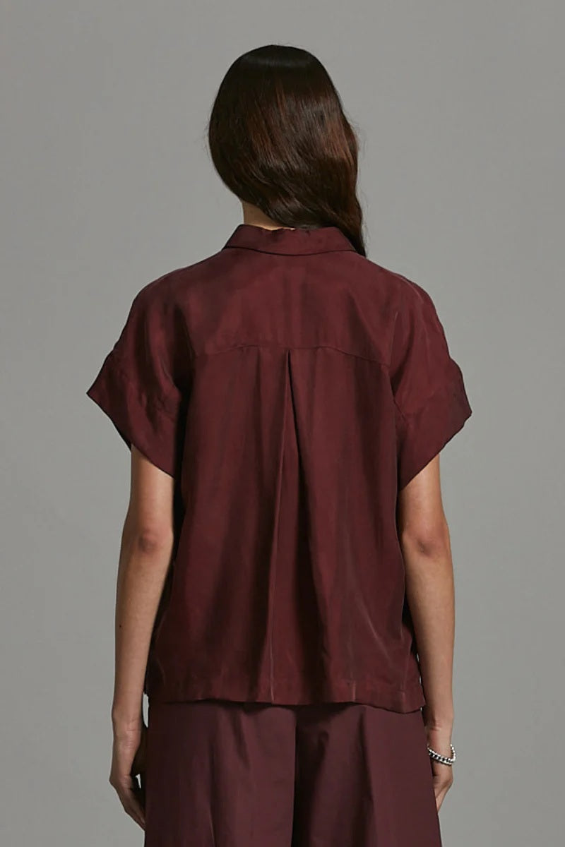 Person wearing a maroon shirt and pants against a gray background