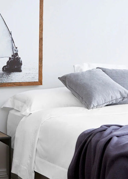 Bedroom with a bed, side table, and framed picture of a sailboat.