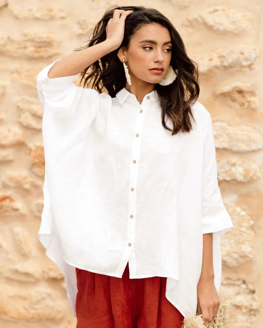 Woman wearing a white blouse and red pants against a stone wall background