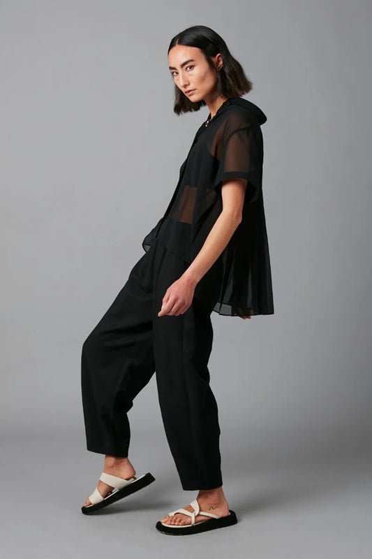 Person wearing a black outfit with sheer sleeves against a gray background