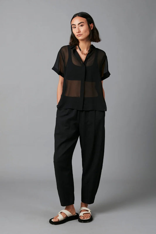 Person wearing a black outfit with sheer top on a gray background