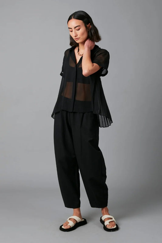 Person wearing a black outfit with sheer top on a gray background