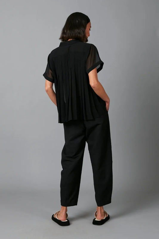 Person wearing a black outfit with sheer sleeves against a gray background