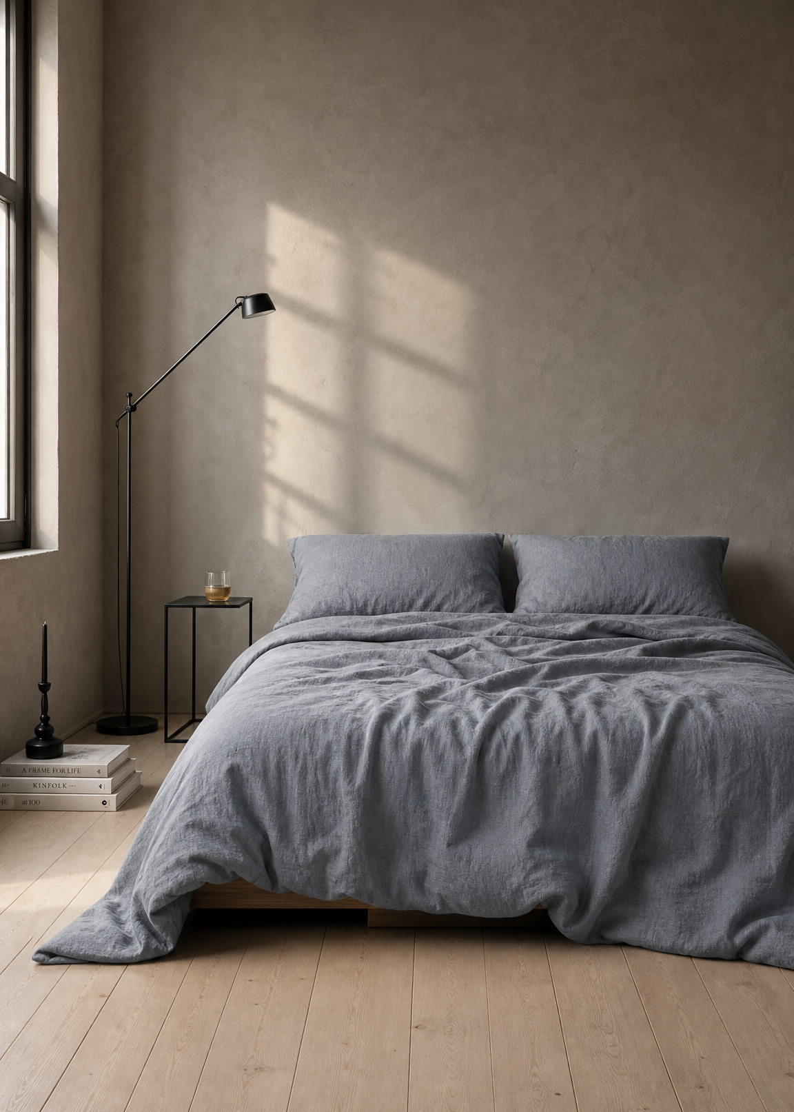 Bedroom with gray bedding and a lamp on a wooden floor.