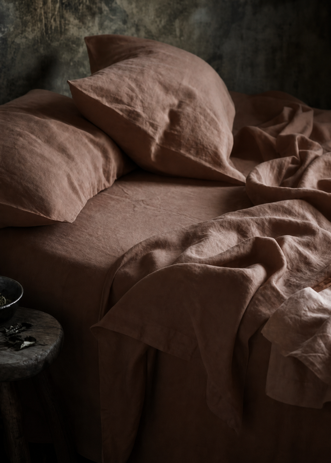 Brown textured pillows and blanket on a bed in a dimly lit room.