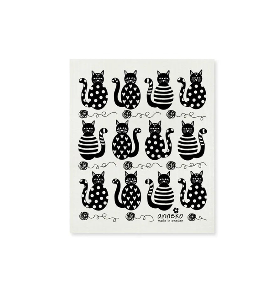 A white dish cloth with a black and polka dot pattern featuring various stylized cat shapes.