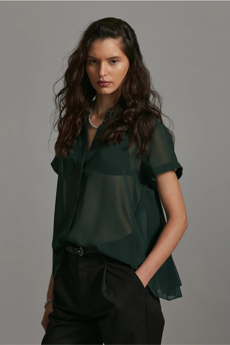 Woman wearing a dark green blouse against a gray background