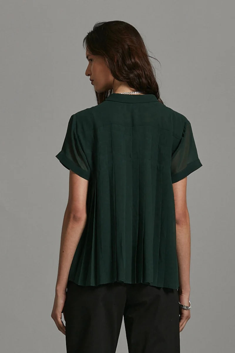 Woman wearing a dark green blouse against a gray background