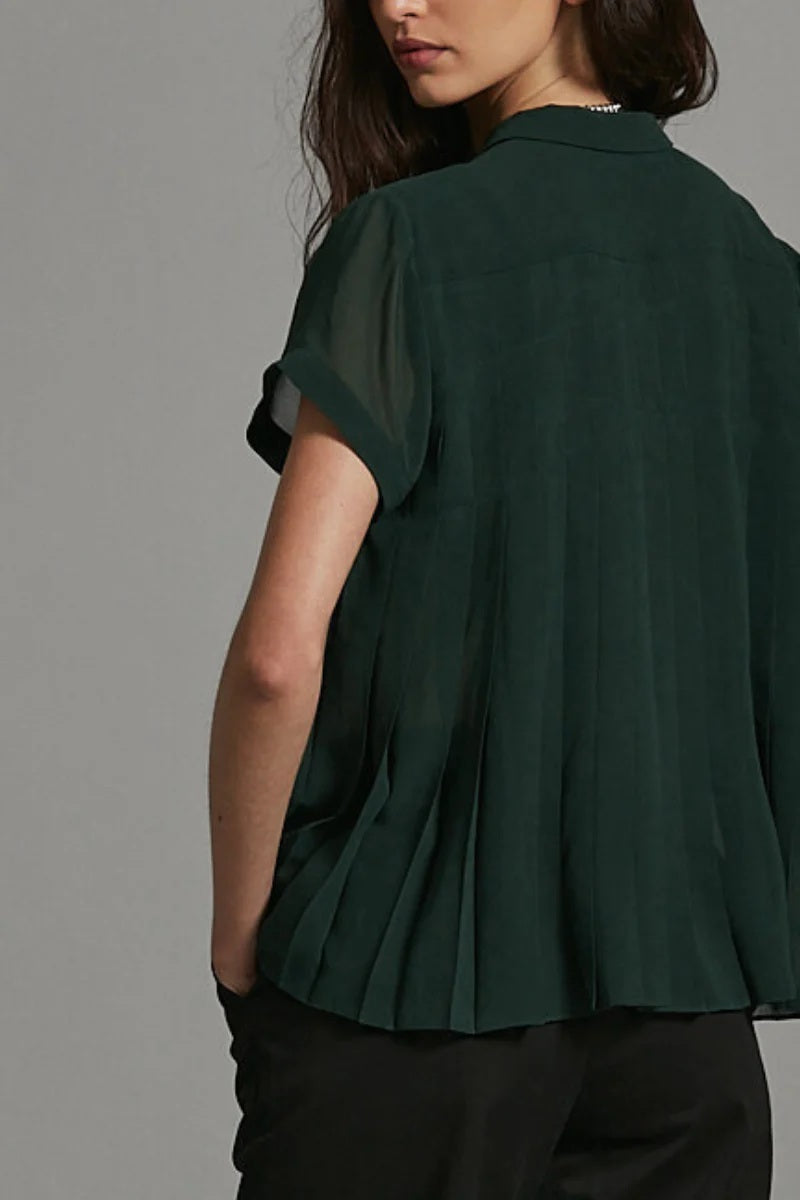 Person wearing a dark green blouse against a gray background