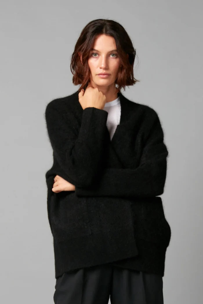 Woman wearing a black sweater against a gray background