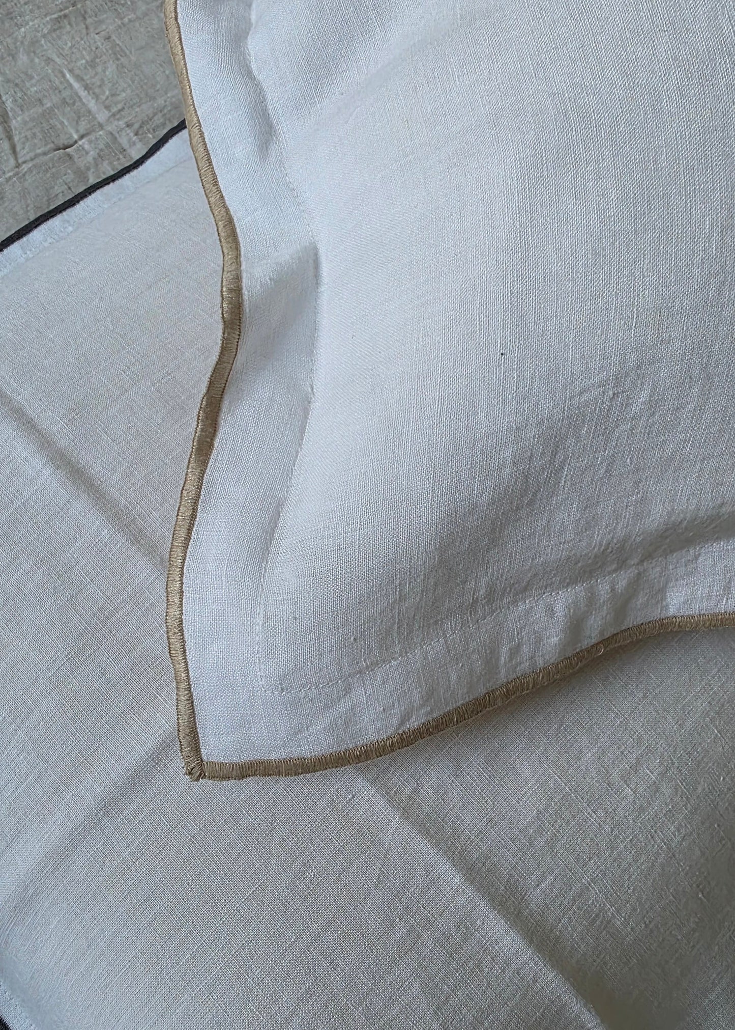 Close-up of white fabric with a gold trim on a neutral background
