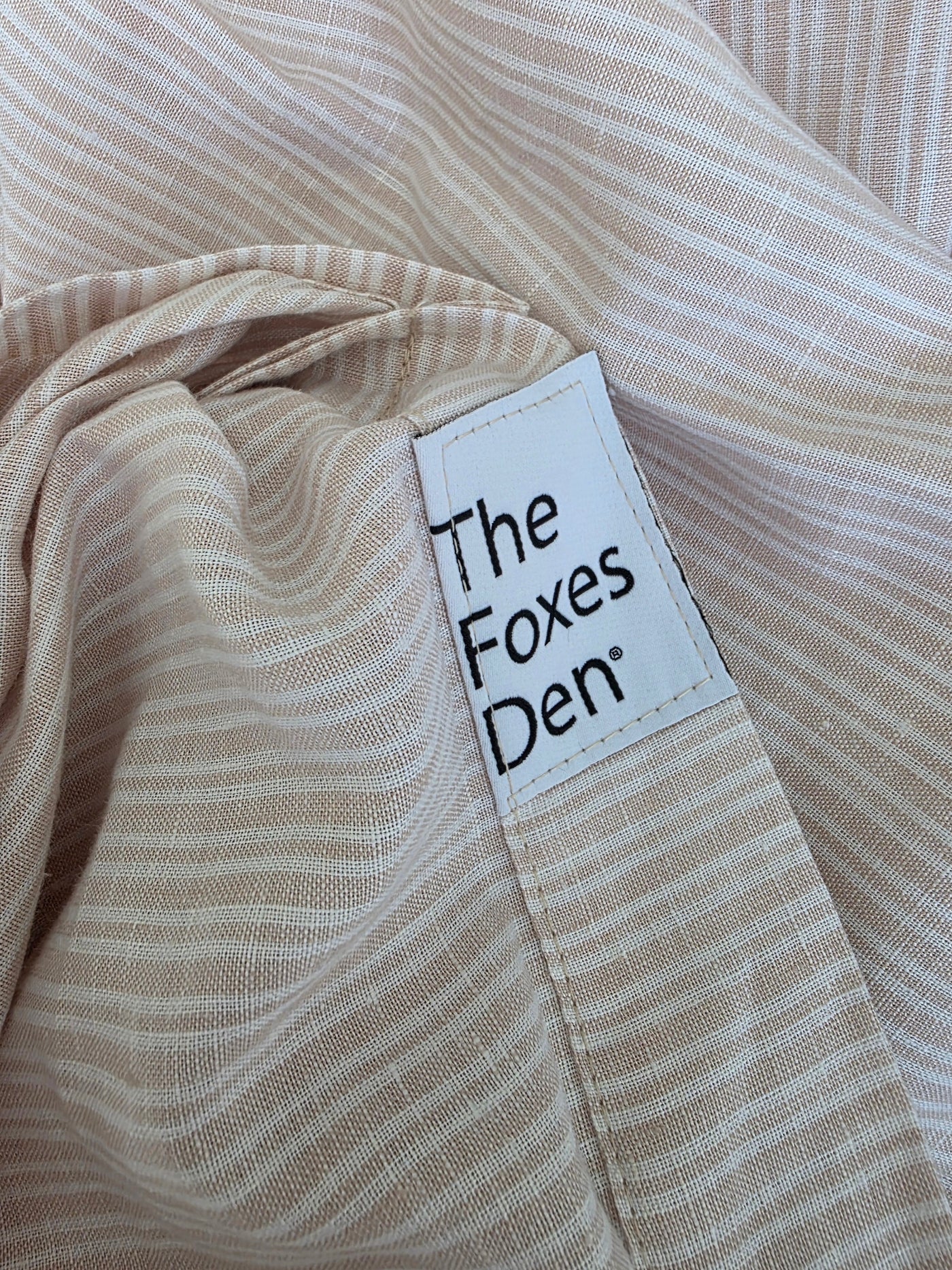 Close-up of beige fabric with a 'The Foxes Den' label.