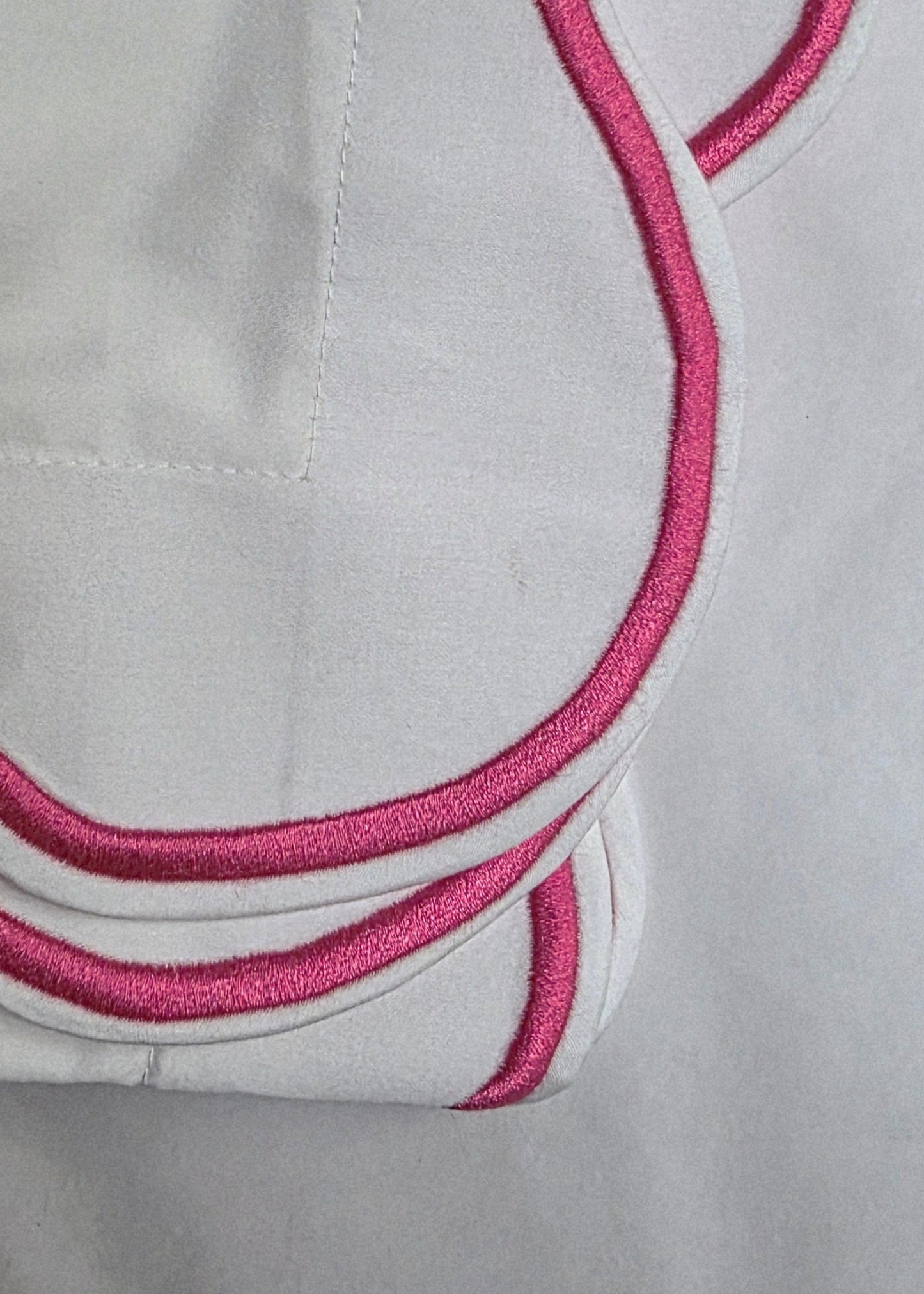 White fabric with pink embroidery on a light gray background