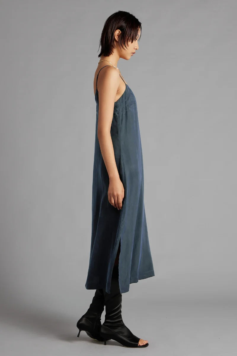 Woman wearing a long, light blue dress against a gray background