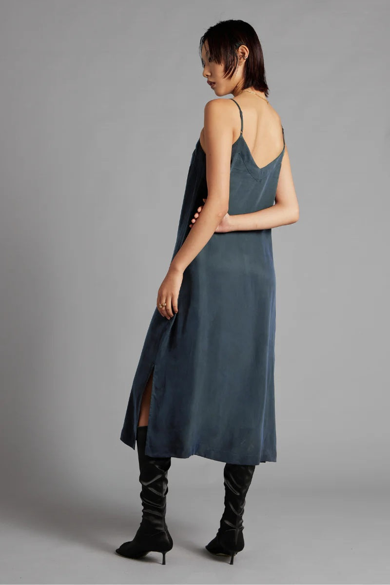 Woman wearing a blue slip dress with a gray background