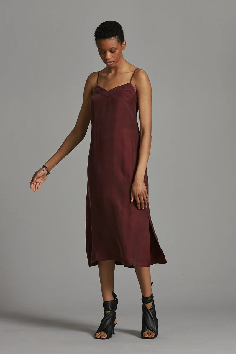 Woman wearing a burgundy slip dress against a gray background