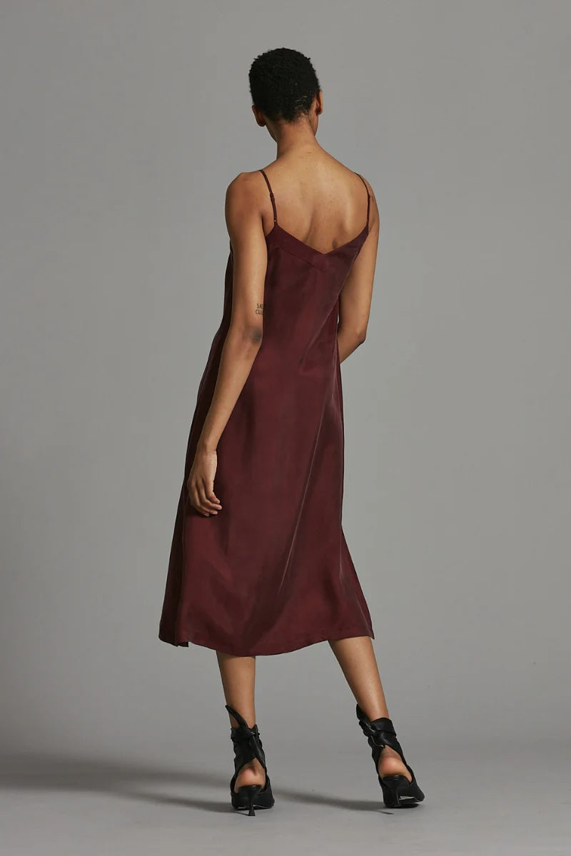Woman wearing a burgundy slip dress against a gray background