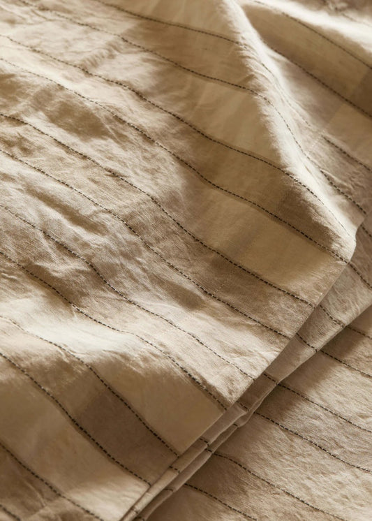 Close-up of beige quilted fabric with visible stitching