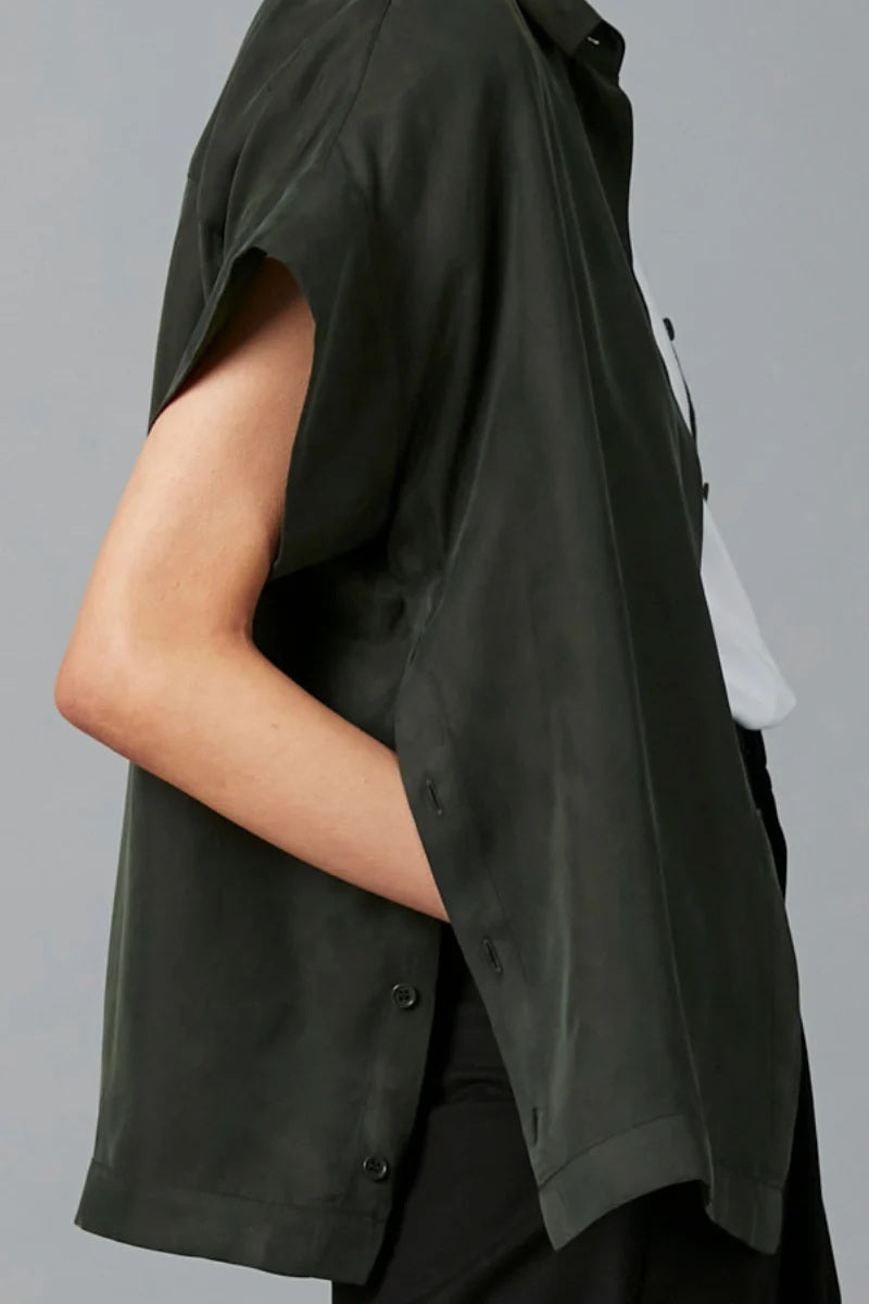 Person wearing a dark green sleeveless shirt against a gray background