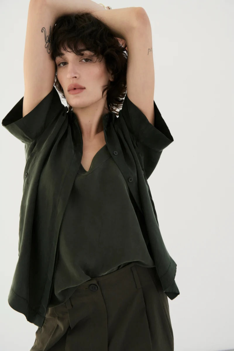 Woman wearing a dark green outfit with a plain background