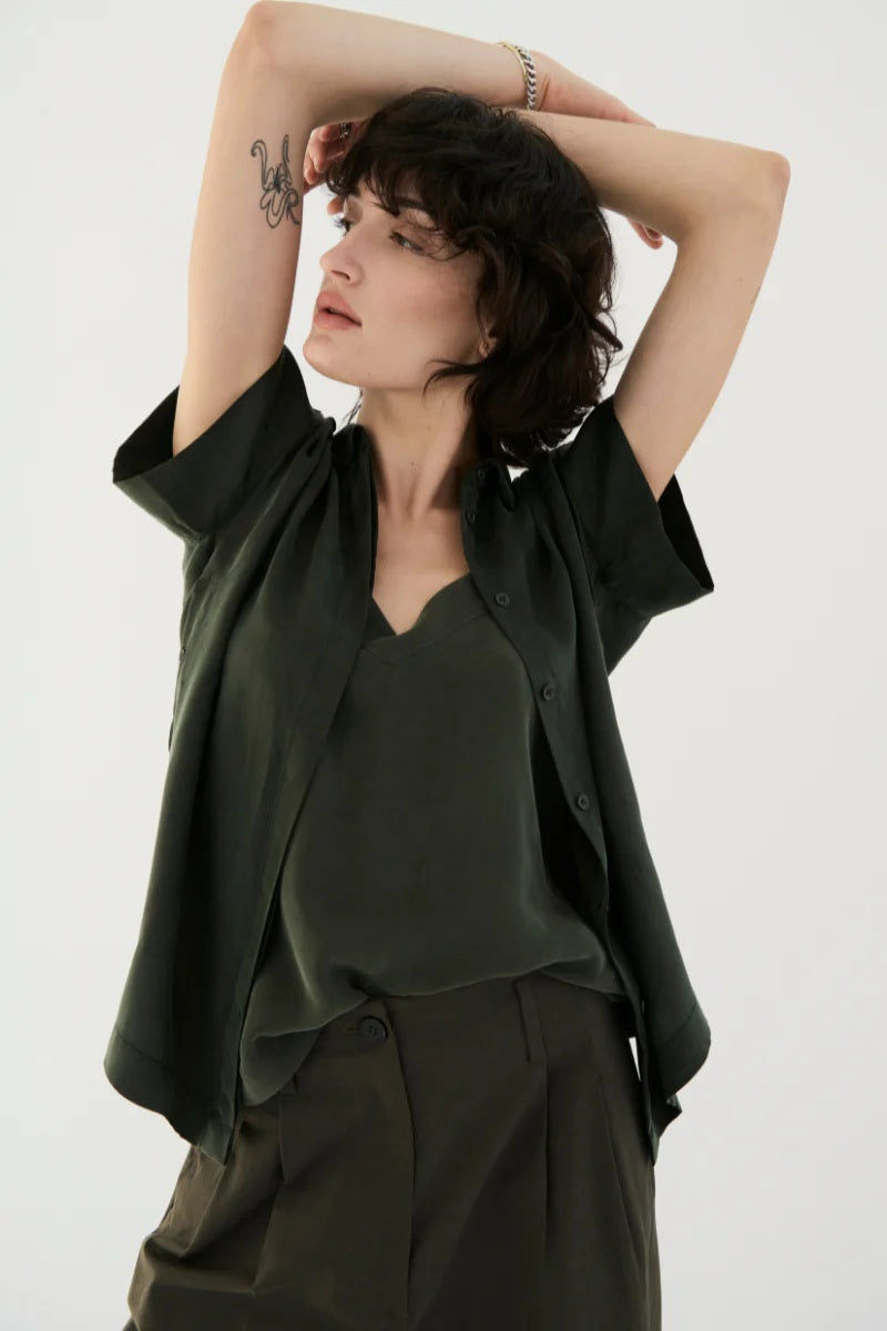 Woman wearing a dark green outfit with a plain background