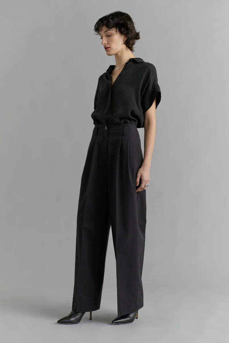 Person wearing a black outfit against a gray background